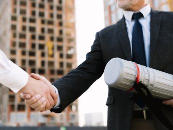 мужчины жмут руки на фоне строительства