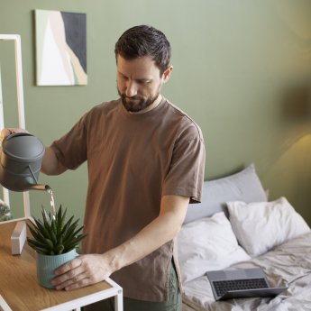 мужчина поливает цветок спальня стеллаж