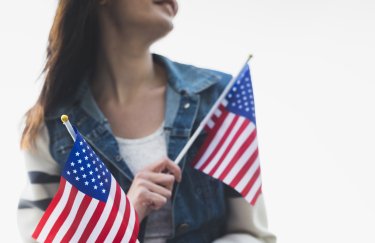 США приостановили рассмотрение заявлений мигрантов. Фото: freepik флаги США, женщина